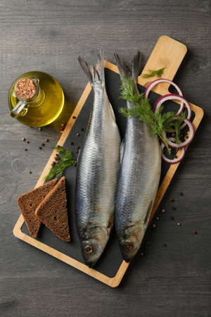 Board with herring fish and spices, and oil on dark wooden backgroundの写真素材