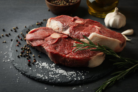 Tray with steak meat with herbs and spices on dark wooden background