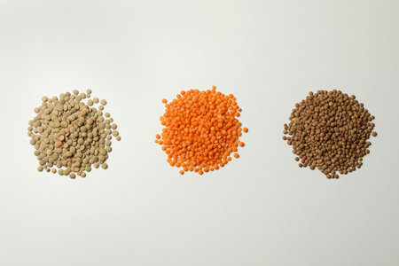 Heaps of different legumes on white background, top view