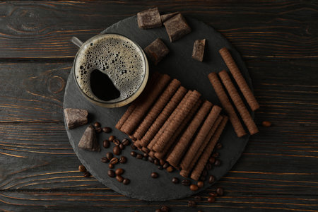 Concept of breakfast with coffee and chocolate wafer rolls on wooden backgroundの写真素材