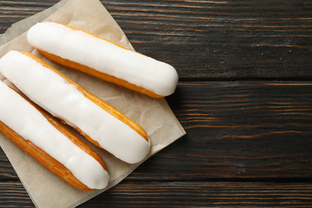 Baking paper with eclairs on wooden background
