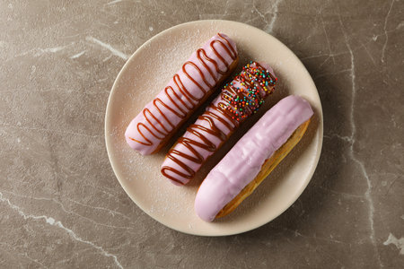 Plate with eclairs with custard on gray background