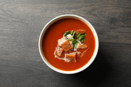 Bowl of tasty tomato soup on dark wooden backgroundの写真素材