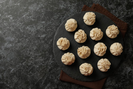 Tray with raw khinkali on kitchen towel on black smokey backgroundの写真素材