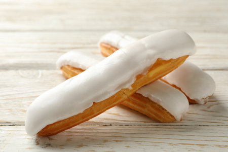 Tasty eclairs with custard on wooden background