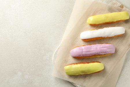 Board with eclairs with custard on white textured backgroundの写真素材