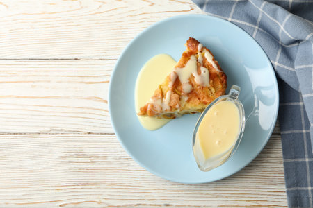 Plate with pie and condensed milk on wooden background with kitchen towelの写真素材