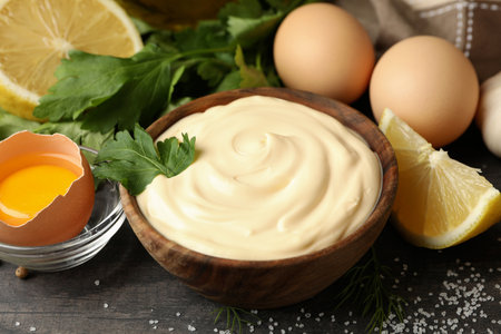 Wooden bowl of mayonnaise and ingredients for cooking, close upの写真素材