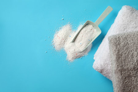 Towels and scoop with washing powder on blue backgroundの写真素材