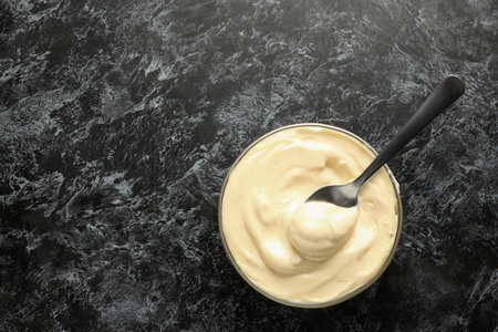Bowl with mayonnaise and spoon on black smokey backgroundの写真素材