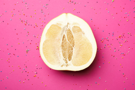 Half of ripe pomelo fruit and sprinkles on pink backgroundの写真素材