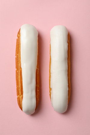 Delicious eclairs with custard on pink background