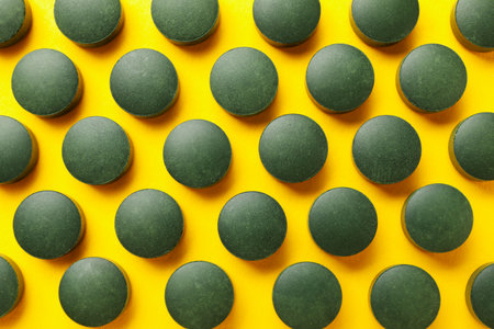 Flat lay with spirulina pills on yellow background, top viewの写真素材