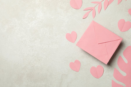 Envelope, paper leaves and hearts on white textured backgroundの写真素材