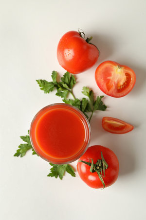 Glass of tomato juice, tomatoes and parsley on white backgroundの写真素材