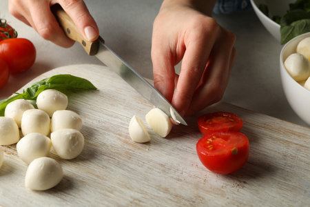 Woman slicing mozzarella on cutting board, close upの写真素材