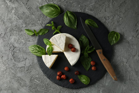 Tray with camembert, hazelnut, basil and knife on gray backgroundの写真素材