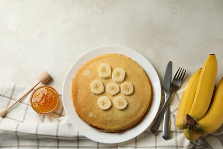 Concept of breakfast with plate of thin pancakes with banana, and jam on white textured backgroundの写真素材