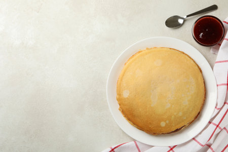 Concept of breakfast with plate of thin pancakes and jam on white textured backgroundの写真素材