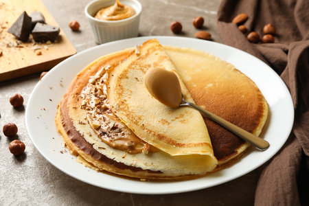 Concept of breakfast with crepes with peanut butter and nuts on gray tableの写真素材