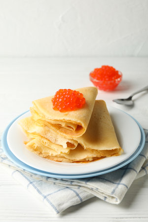 Concept of breakfast with plate of crepes with red caviar on white wooden tableの写真素材
