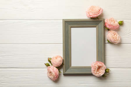 Roses and blank frame on white wooden backgroundの写真素材