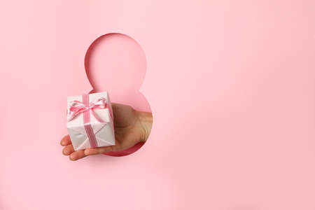 Paper cut Eight and female hand hold gift box on pink background