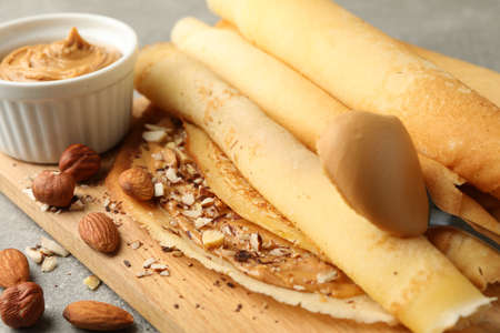 Concept of delicious breakfast with crepes with peanut butter and nuts on gray tableの写真素材