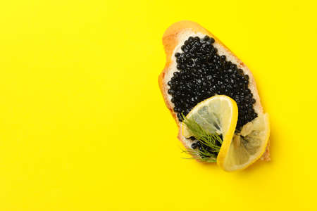 Delicious sandwich with black caviar on yellow backgroundの写真素材