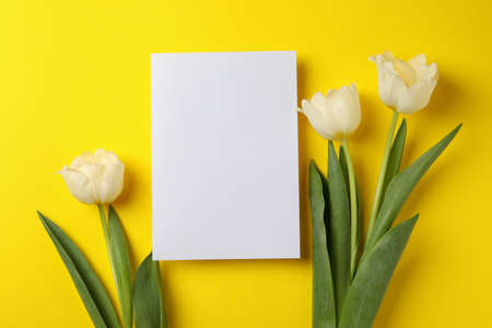 Tulips and blank card on yellow background, space for text