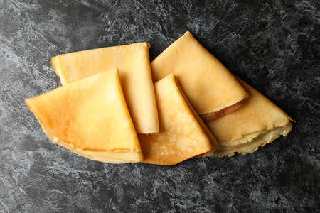 Delicious thin pancakes on black smokey background