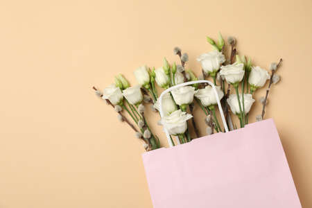 Pink paper bag with roses and willow catkins on beige backgroundの写真素材