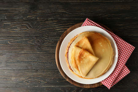 Board with thin pancakes on wooden backgroundの写真素材