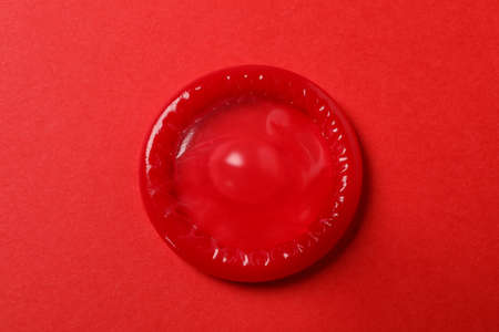 Single red condom on red background, top viewの写真素材