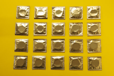 Flat lay with blank condoms on yellow background