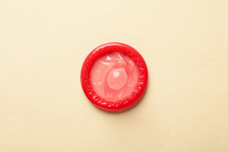 Single red condom on beige background, top viewの写真素材
