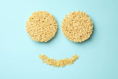 Happy face made of instant noodles on blue backgroundの写真素材