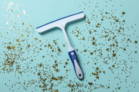 Window cleaning squeegee on blue background with glitter