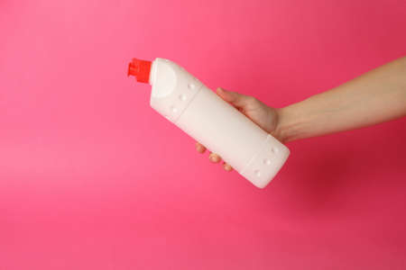 Female hand hold blank detergent bottle on pink backgroundの写真素材
