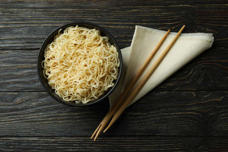 Napkin with chopsticks and bowl with noodles on wooden backgroundの写真素材