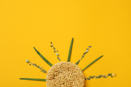 Sun made of instant noodles and spices on yellow backgroundの写真素材