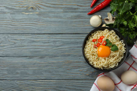 Bowl of cooked noodles and ingredients on wooden backgroundの写真素材