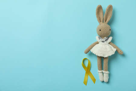 Toy bunny and childhood cancer awareness ribbon on blue backgroundの写真素材