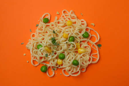 Cooked noodles with vegetables and spices on orange backgroundの写真素材