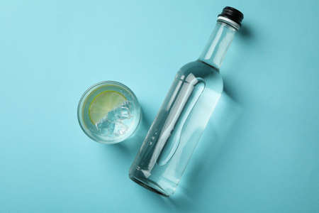 Bottle and glass of vodka with lime on blue backgroundの写真素材