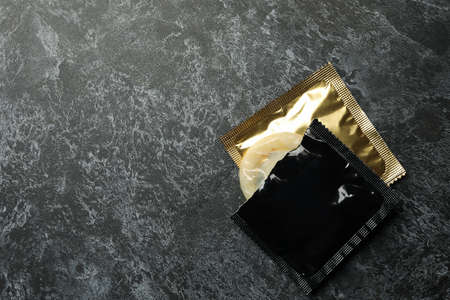 Condoms on black smokey background, space for text