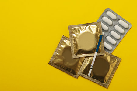 Pregnancy test, condoms and pills on yellow backgroundの写真素材