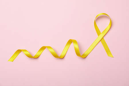 Yellow awareness ribbon on pink background, space for textの写真素材