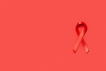 Red awareness ribbon on red background, space for textの写真素材