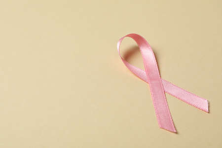 Pink awareness ribbon on beige background, space for textの写真素材